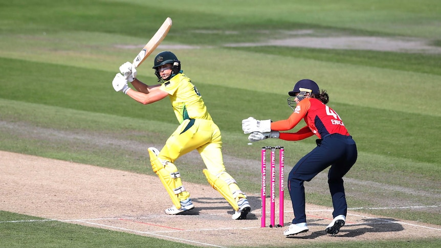 Australia's Ellyse Perry hits the ball as a wicket keeper tries to stop it.