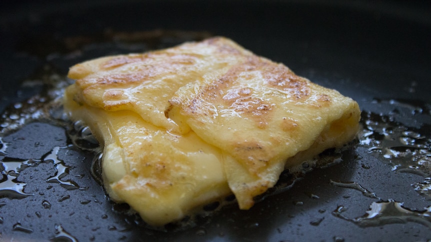A folded crepe, oozing with cheese, fries in oil.
