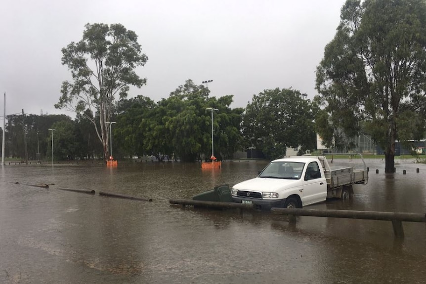 A white ute is parked near the softball fields which are submerged as the wind picks up at Carina
