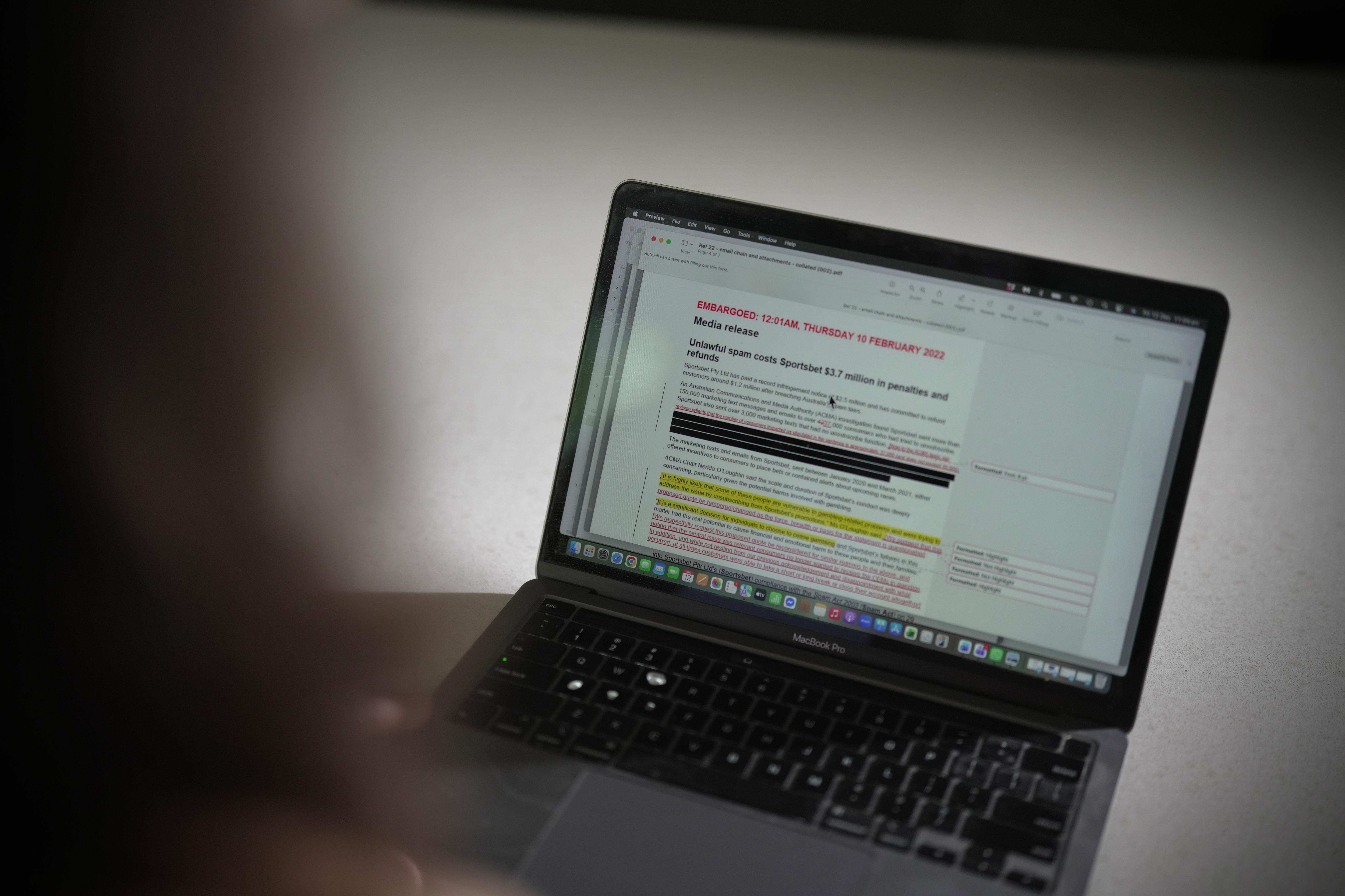 Close do comunicado de imprensa embargado sobre apostas esportivas em um laptop com alterações e redações ao longo do texto.