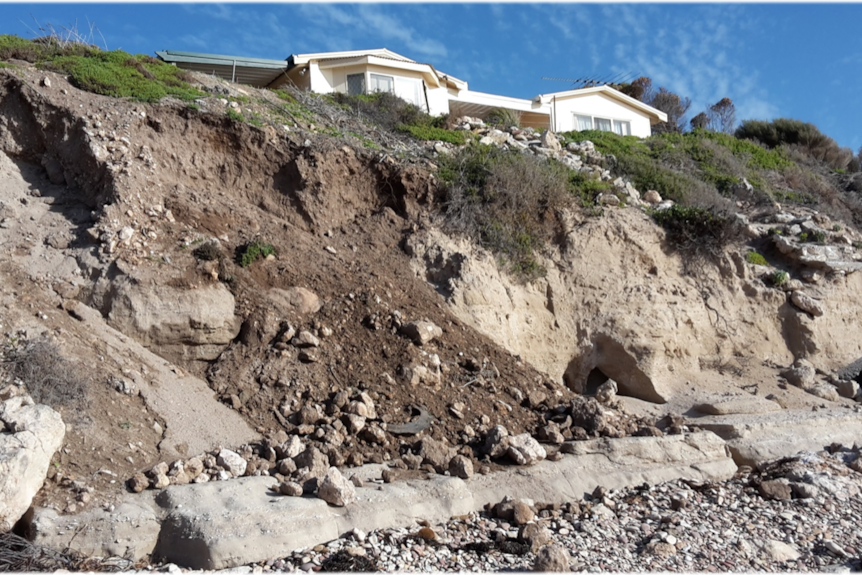 A white beach shack just few meters away from a cliff caused by storm erosion at Point Turton in South Australia.