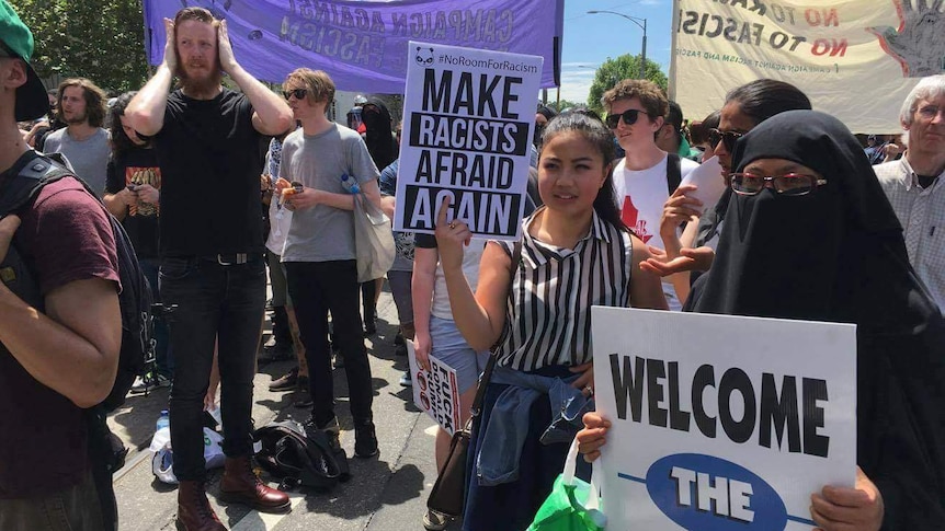 Woman with a sign saying Make racists afraid again