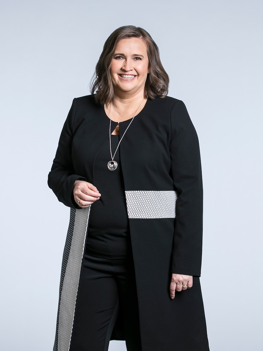 Kate Jenkins standing for a portrait, wearing black.