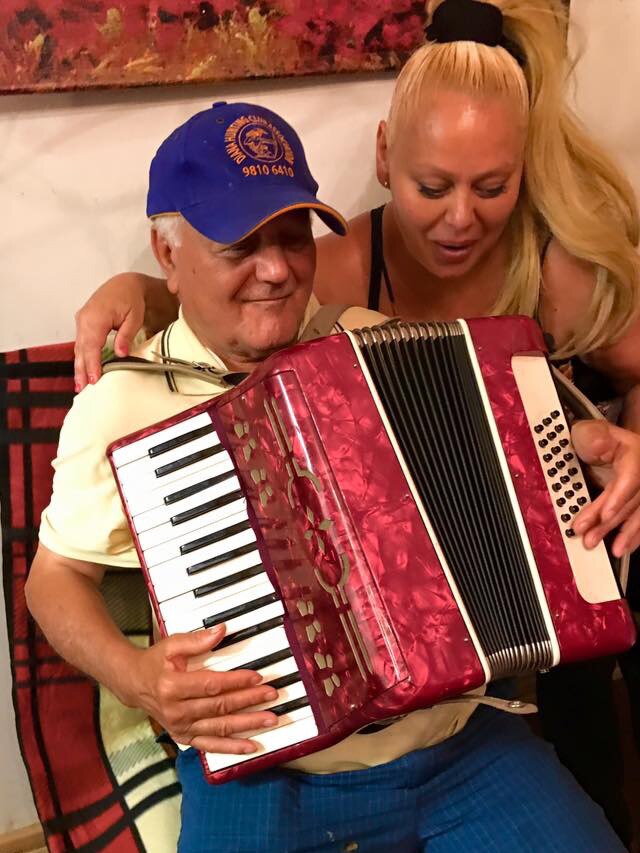 Luigi playing the piano accordion with his daughter smiling.