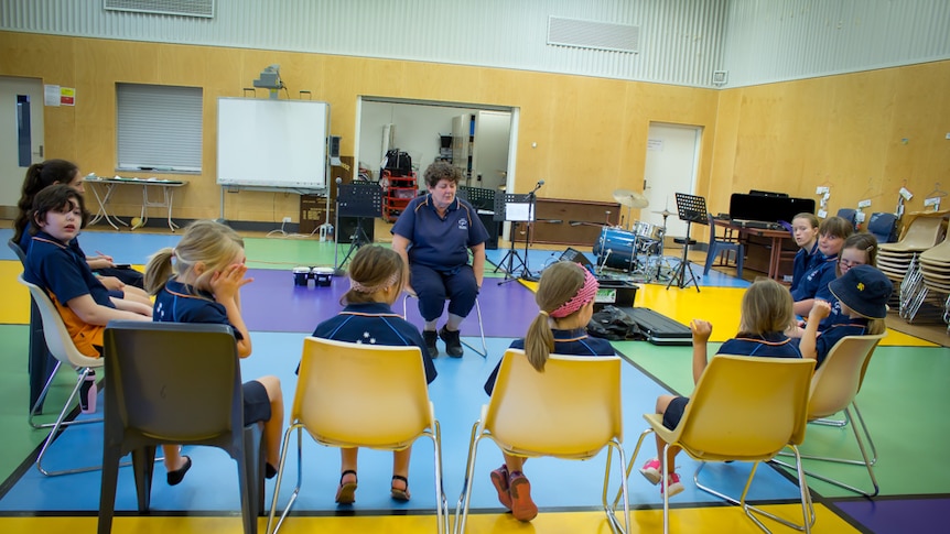 Girl Guides sit in semi circle in school gym.