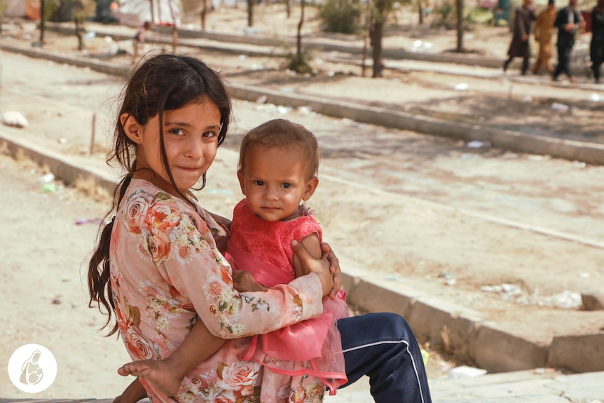 A child with a baby on her knee