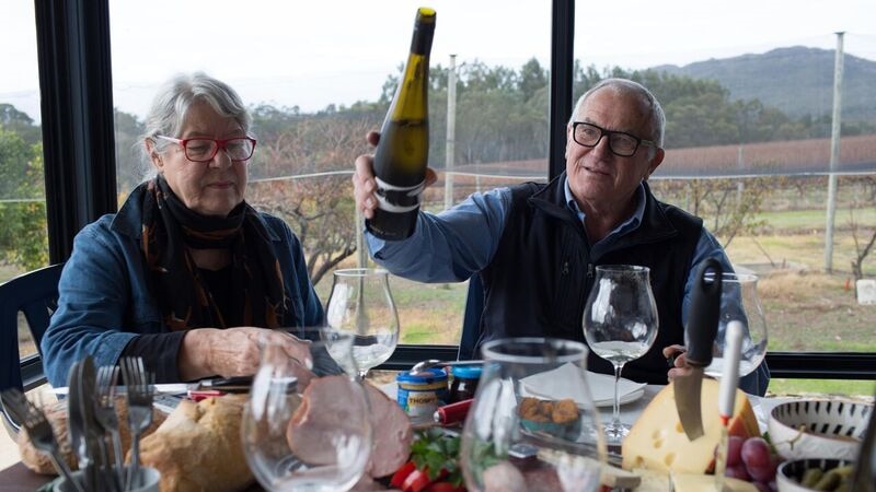 An older couple pour a glass of wine