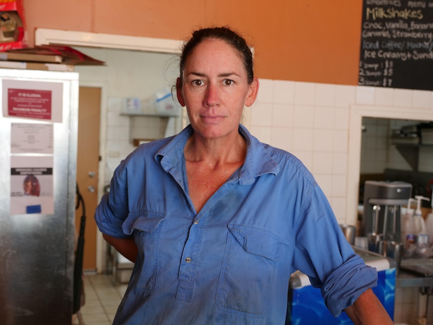 A woman wearing a blue, long-sleeved shirt looking directly at the camera.