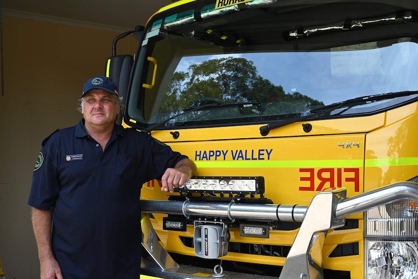 Happy Valley Rural Fire Brigade volunteer firefighter Darren Gorlick stands beside a fire truck.