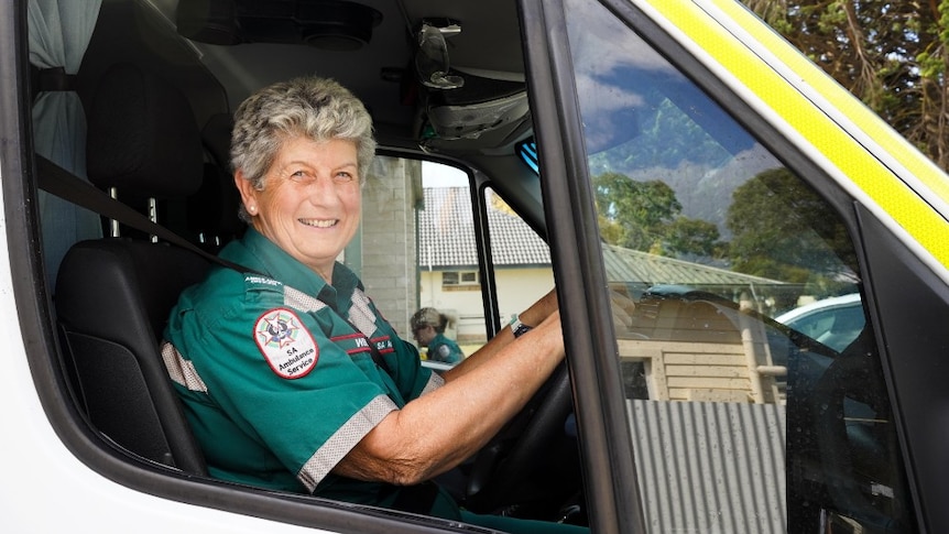 Wendy Hollick smiles in her SA Ambulance uniform from the wheel of an ambulance.