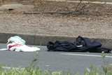 A bloodied towel and police uniform lay on the road.