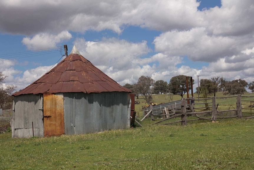 Old rusted round farm building and fenced pen