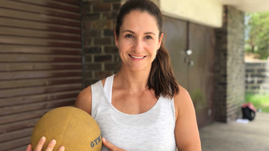 A woman personal trainer holding a medicine ball
