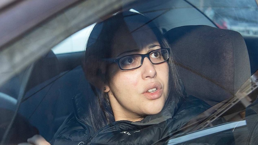 Lydia Abdelmalek, dressed in a black puffy jacket, looks out the car passenger seat window with concern.