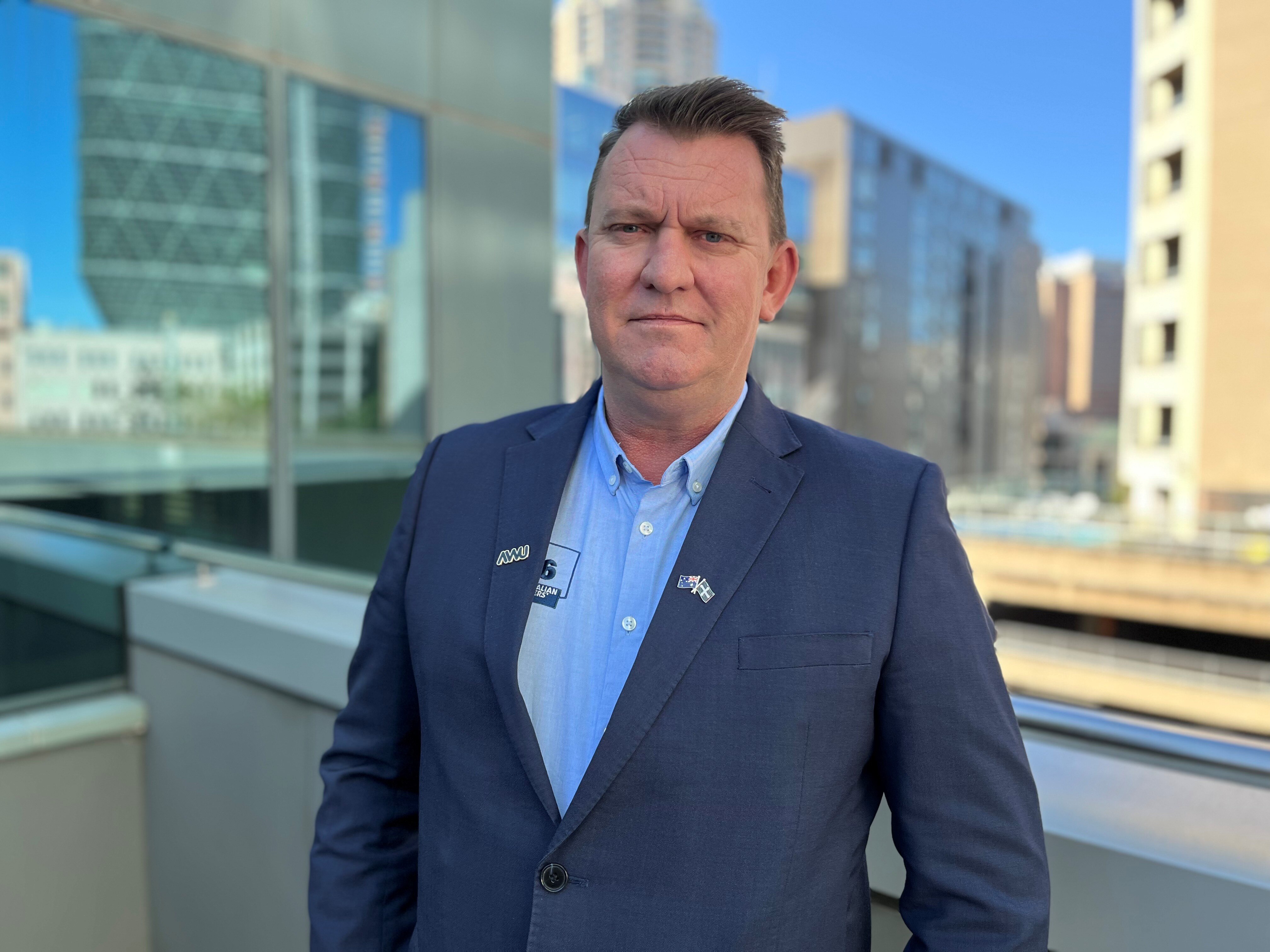 A portrait photo of Paul Farrow on a terrace with highrises in the background