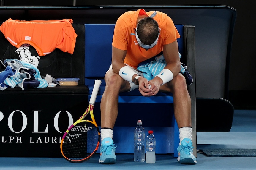 A downcast Rafael Nadal on a seat.