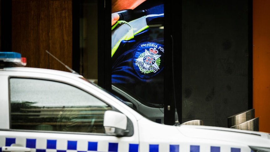 A Victoria Police car is parked in front of a billboard with a Victoria Police uniform close up