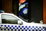 A Victoria Police car is parked in front of a billboard with a Victoria Police uniform close up