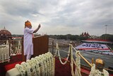 Prime Minister Modi surrounded by garlands and wearing white and orange addresses the nation.