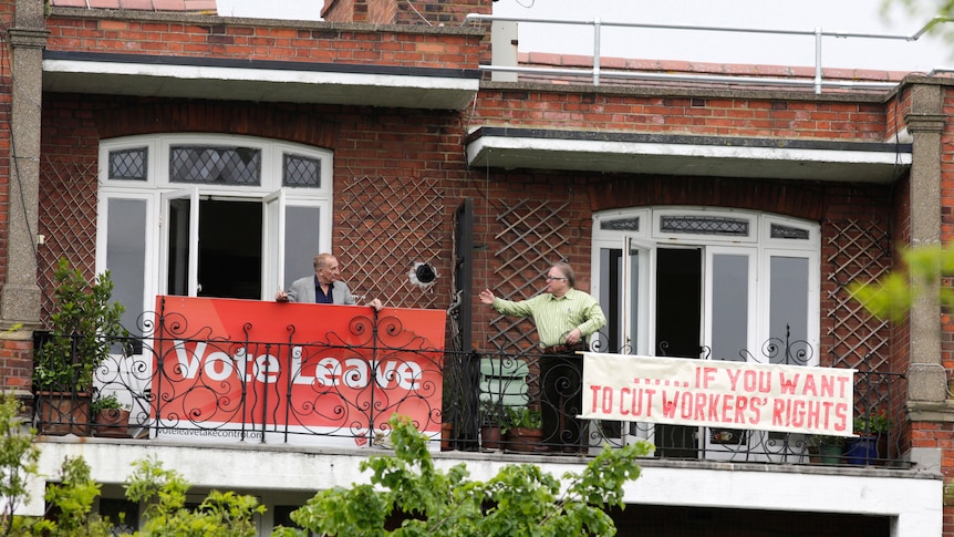 Two London neighbours hold rival Brexit signs: left reads "Vote Leave", right reads "…if you want to cut workers rights"
