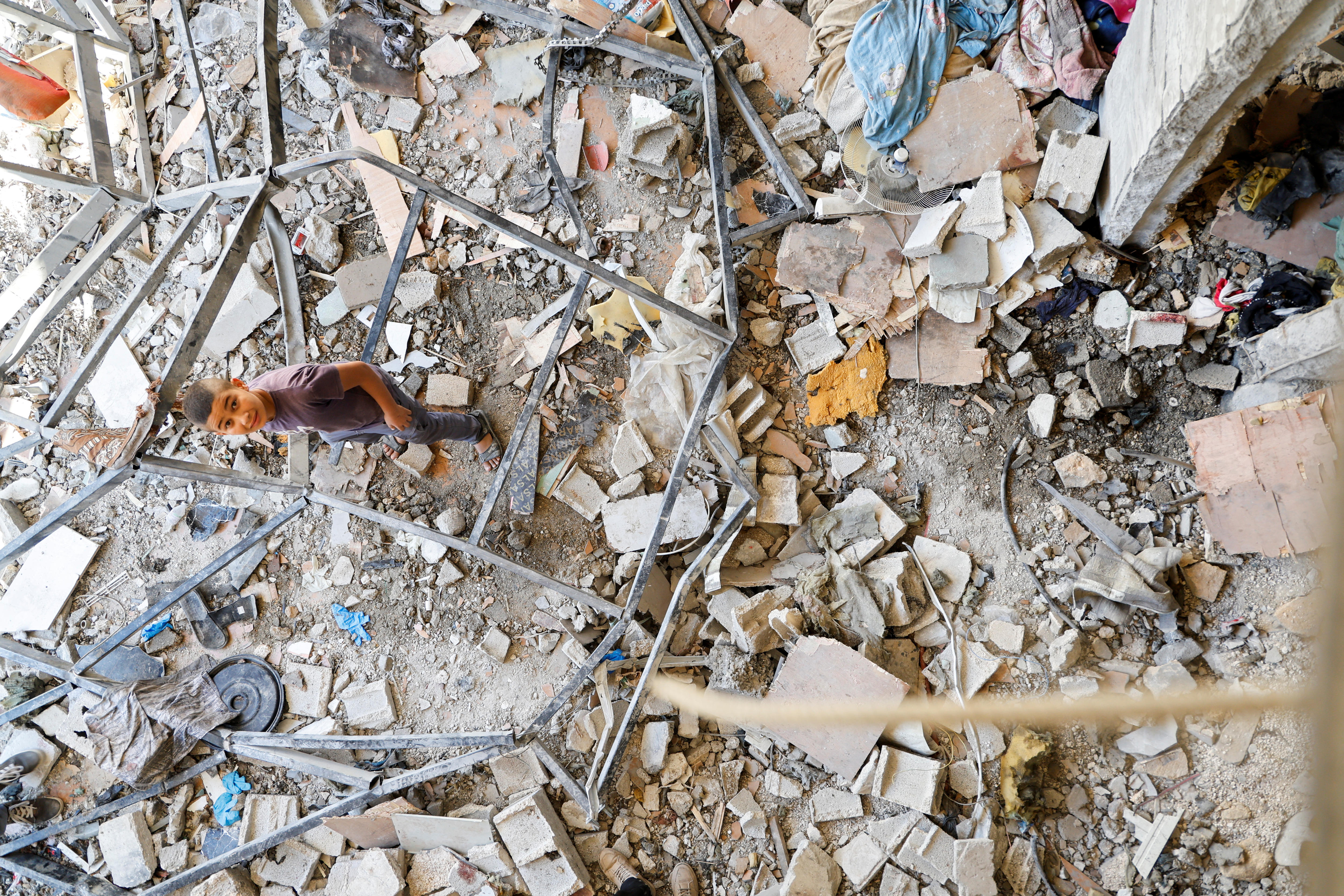 A top-down view of a child standing amongst rubble.