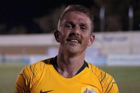 Red haired man with moustache wearing yellow jersey on soccer field