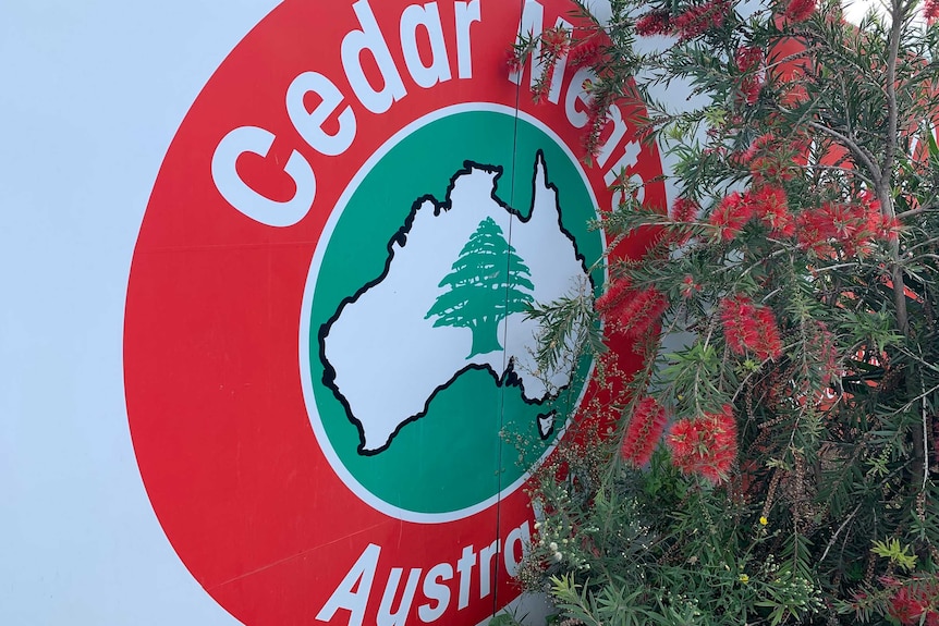 A close-up photograph of the Cedar Meats Australia logo, next to a bottlebrush tree.