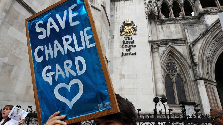 Protester hold 'Save Charlie Gard' placard in front of The Royal Courts of Justice sign