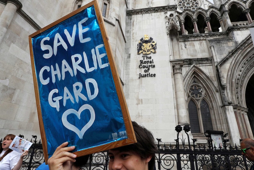 Protester hold 'Save Charlie Gard' placard in front of The Royal Courts of Justice sign