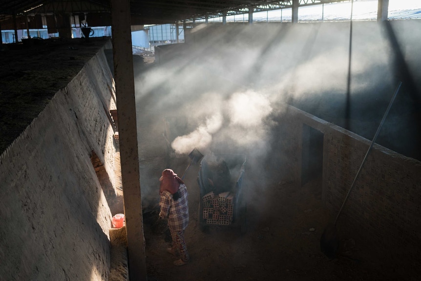 A woman cleans ash from a brick kiln in Cambodia.