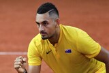 Nick Kyrgios, wearing Australian colours, celebrates at the net after winning a point.