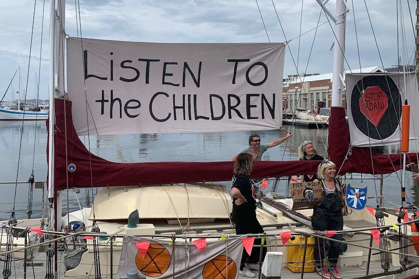 A boat at Hobart's waterfront bears a sign that reads "listen to the children"