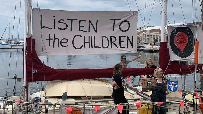 A boat at Hobart's waterfront bears a sign that reads "listen to the children"