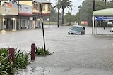 A car in a street that has been inundated by floodwater.