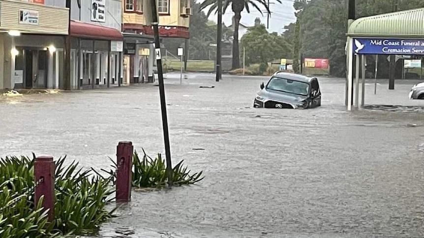 A car in a street that has been inundated by floodwater.