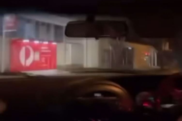 A post office as seen through the windscreen of a car at night.