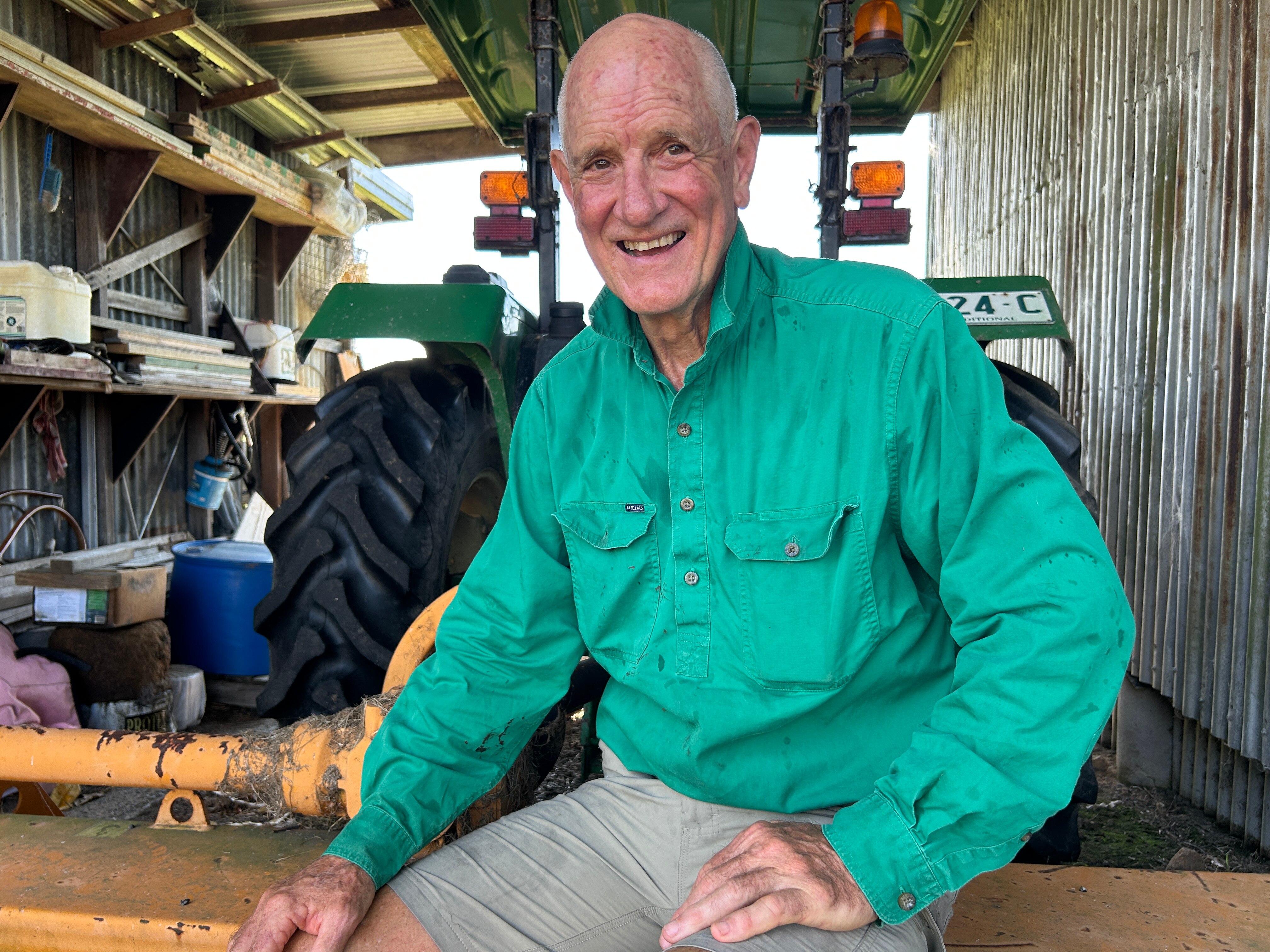 Man in green work shirt in front of tractor