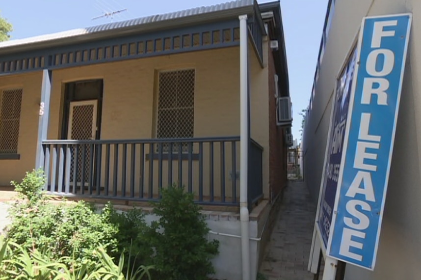 A house with a veranda and a for lease sign outside, leaning against wall