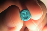 A person holds a tablet containing MDMA in their fingertips.