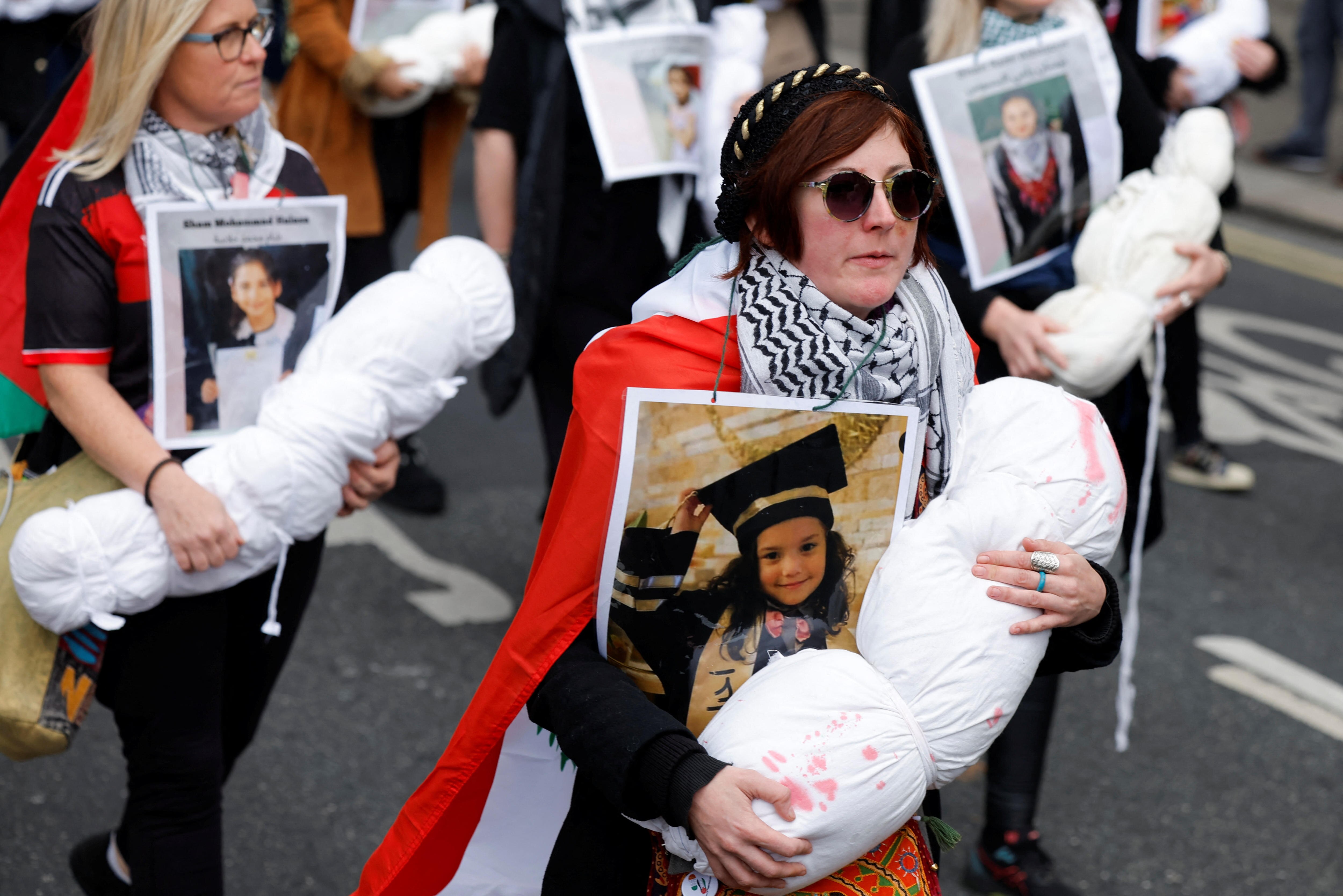 A small crowd of people holding bundles and pictures in their arms.