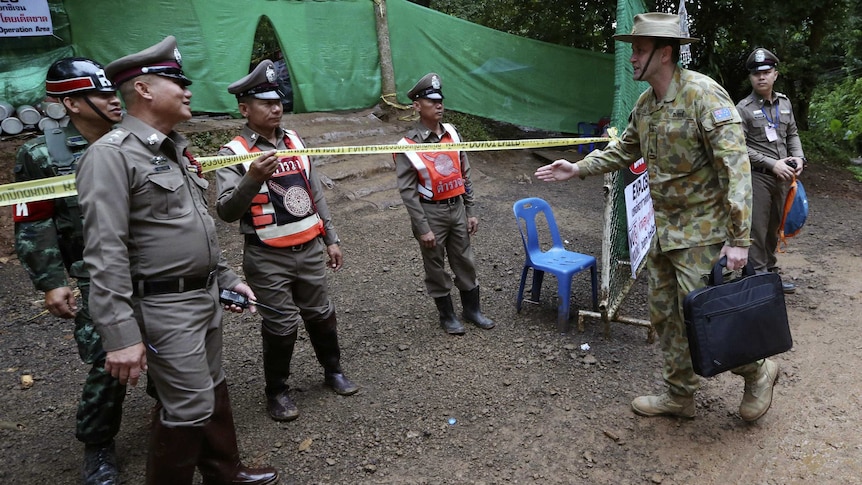 An Australian Defence Force member arrives at the security tape near the cave entrance.