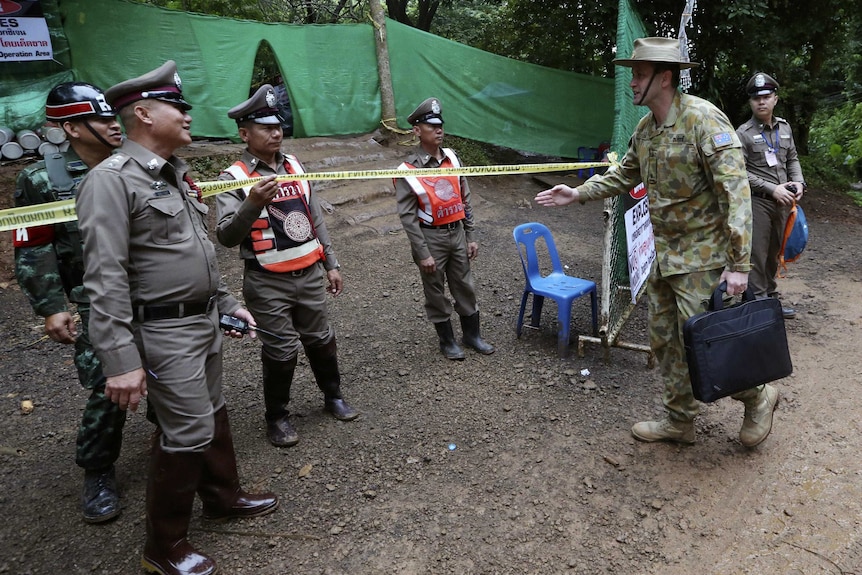 An Australian Defence Force member arrives at the security tape near the cave entrance.