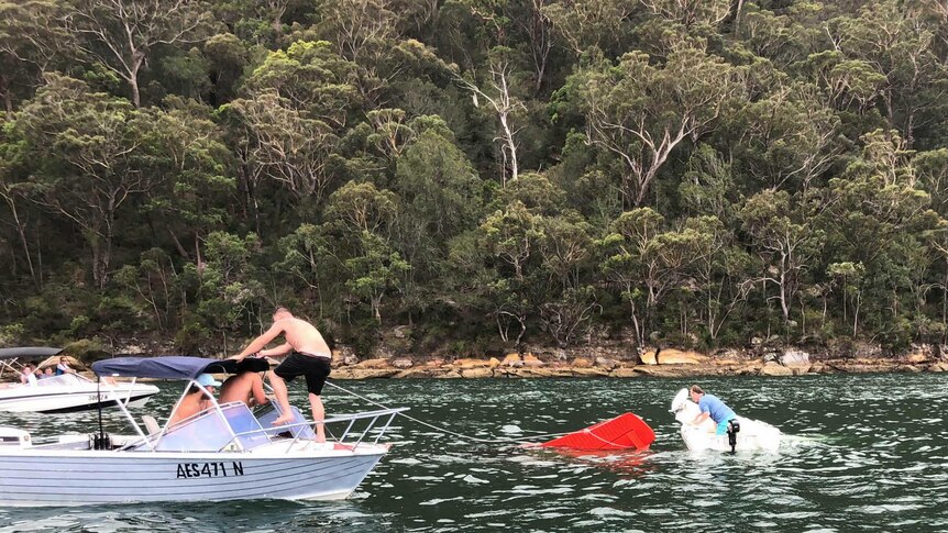 Witnesses attempt to rescue a Sydney seaplane sinking into the Hawkesbury River at Cowan on New Year's Eve, December 31 2017.