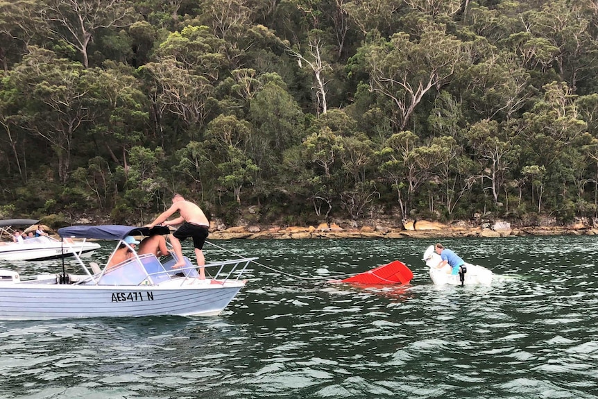 Witnesses attempt to rescue a Sydney seaplane sinking into the Hawkesbury River at Cowan on New Year's Eve, December 31 2017.