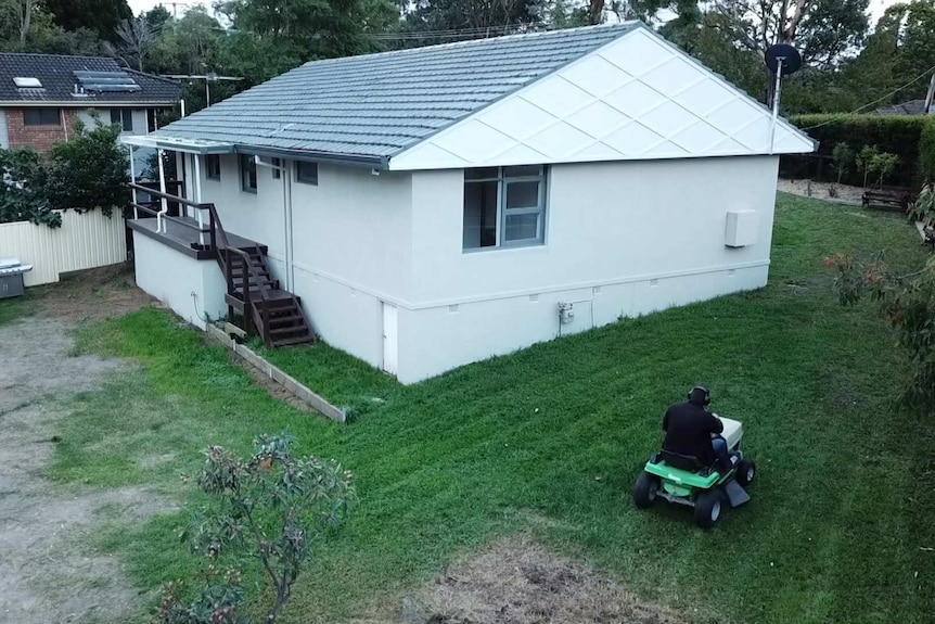 Michael Neal mowing the lawn of his house on a ride-on mower