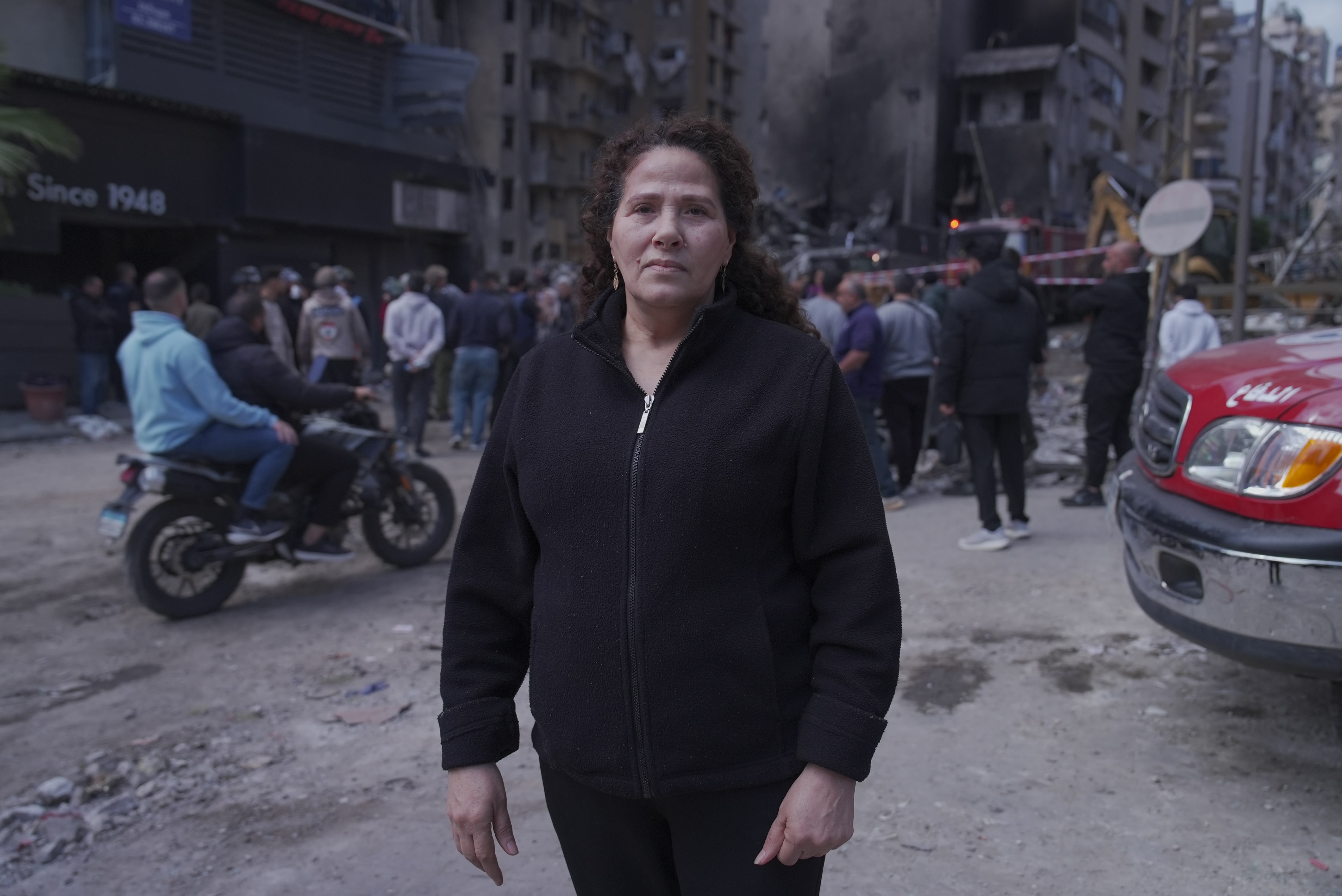 A woman stands on a street that has been bombed.