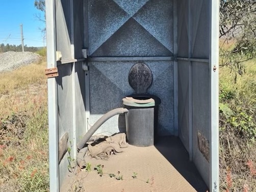 A toilet cubicle with no door on the front.