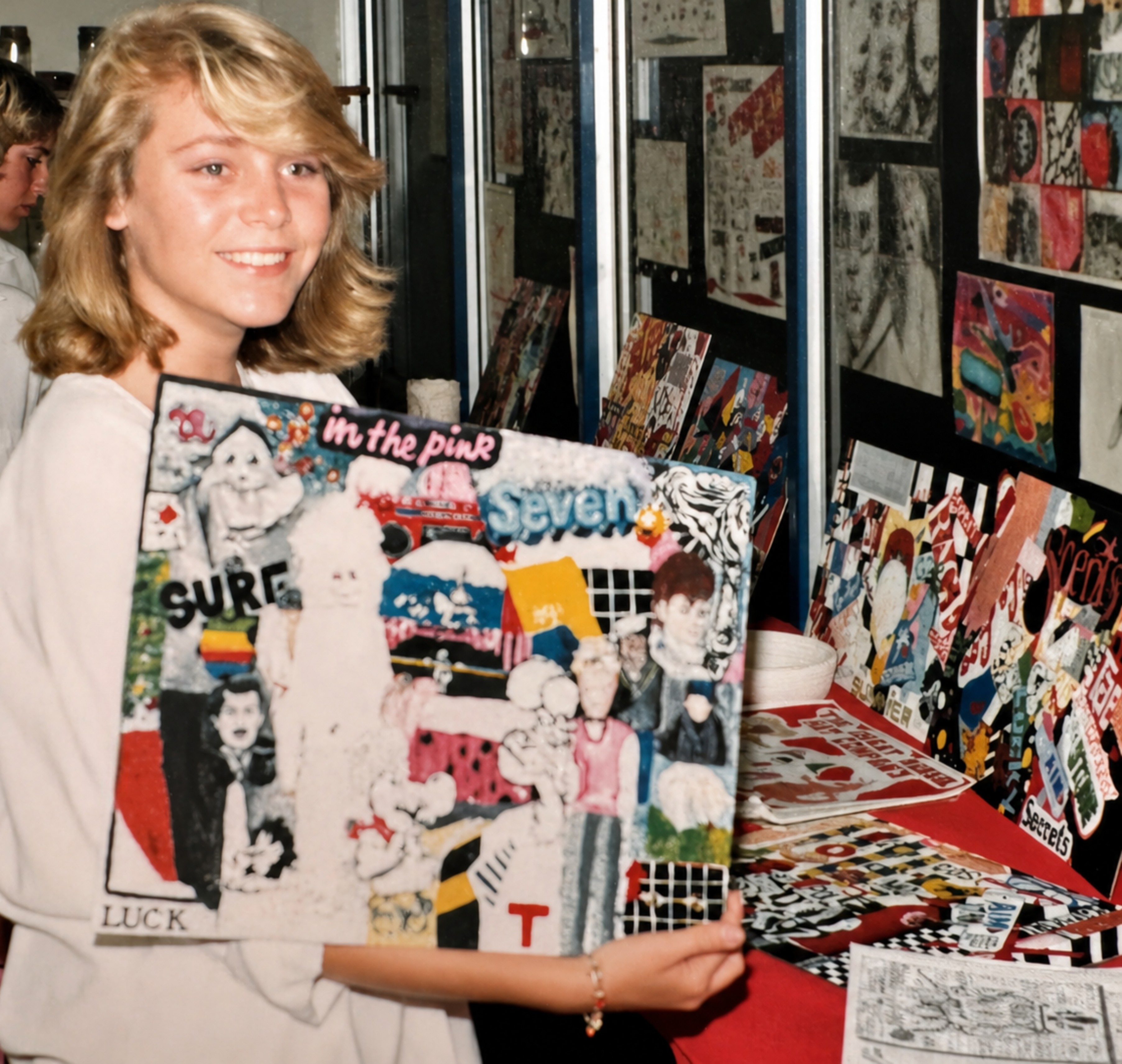 Young girl smiles with scrapbooked art in front of wall of exhibit