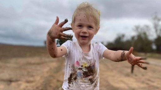 Child in gumboots plays in mud.