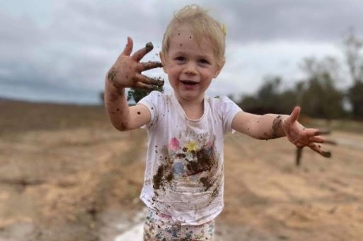Child in gumboots plays in mud.